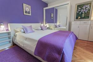 特罗吉尔Apartments & Rooms Trogir Stars FREE PARKING的紫色卧室配有一张大床和紫色毯子