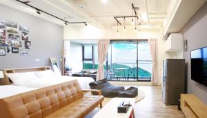 Hsin-hsing宜蘭頭城溫泉海景無邊際泳池豪華套房的一间卧室配有一张床、一张沙发和一个大窗户