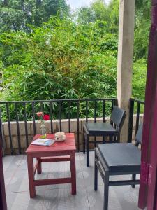 万荣Dokchampa Hotel的阳台上配有两把椅子、一张桌子和一张桌子及椅子