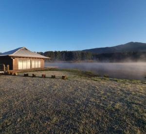 霍维克eKuthuleni - Wooden Cabin over the lake的田野前有雾的建筑物