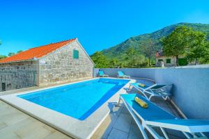 扎格沃兹德Your Ideal Haven for Serene Relaxation Villa Roglić near Baška Voda的一个带椅子的游泳池以及一座房子