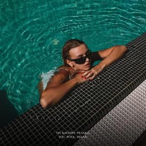 敖德萨M1 Club Hotel的戴太阳镜的游泳池里的女人