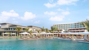 拉斯阿尔卡麦InterContinental Ras Al Khaimah Mina Al Arab Resort & Spa, an IHG Hotel的一个带椅子和遮阳伞的游泳池的度假酒店
