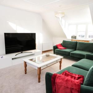 罗宾胡兹贝Falconhurst的客厅配有两张绿色沙发和一台电视机