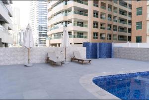 迪拜1BHK luxury Apartment with Marina veiw的一个带椅子的庭院、一个游泳池和一座建筑