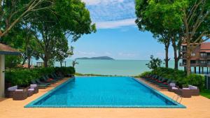 珍南海滩兰卡威波浪别墅度假村的度假村的游泳池配有椅子和海洋