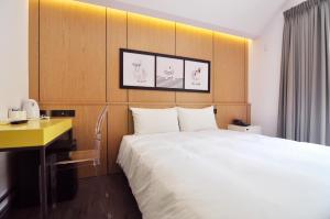 台中市逢甲25行館Fengjia 25 Hotel的酒店客房设有一张大床和一张书桌。