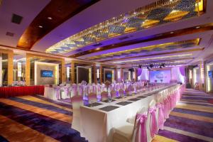 珠海珠海来魅力假日酒店-拱北口岸店的配有长桌子和白色桌椅的房间