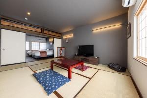 高山Guest House HINATA - Japanese House with Sauna and Open-air Bath的客厅配有电视、桌子和床。