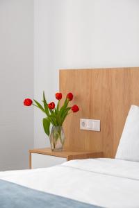 巴统Mariinsky Boutique Hotel的睡前的床头柜上,花朵红色的花瓶