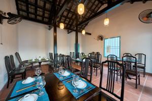 会安Hoi An Legend Charm Boutique Hotel的一间在房间内配有桌椅的餐厅