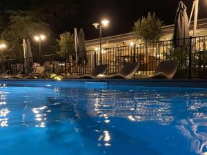 莱斯卡尔波城比利牛斯诺富特酒店的夜间游泳池,配有椅子和遮阳伞
