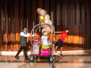 迪拜迪拜古赖尔瑞士酒店的推着满载行李和气球的汽车的人