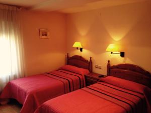 梅迪纳塞利Hostal Nicolás的两张位于酒店客房的床铺,配有红色床单