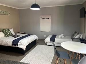 比勒陀利亚Guesthouse @ 31 Murray的卧室配有两张床、一张桌子和一张桌子以及椅子。