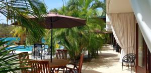 简蒂埃尔Boutique Hotel & Apartments Route 66 Curacao的游泳池旁配有遮阳伞的桌椅