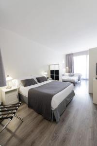 巴塞罗那卡拉布里亚雅典娜公寓式酒店的一间白色的大卧室,配有两张床和一张沙发