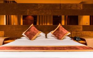 马斯喀特City Park Hotel Apartments的一张带两个枕头的床和一部电话