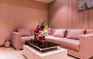 马斯喀特City Park Hotel Apartments的客厅配有沙发和鲜花,桌子上