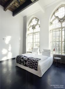 科隆奎斯特隐居酒店的白色卧室设有一张大床和两个窗户