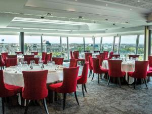 里昂索菲特里昂贝勒库尔酒店的用餐室配有桌子和红色椅子