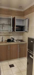 乌姆莱季همم للوحدات السكنيه المخدومة- الدقم的厨房配有木制橱柜和黑色冰箱。