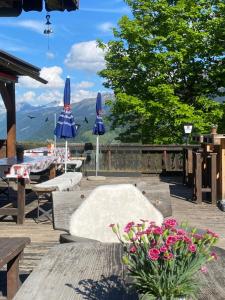 马里克斯Bergpension Battagliahütte的一个带桌子、蓝色遮阳伞和鲜花的庭院