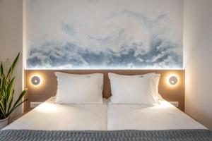 普拉塔尼亚斯蓝色圆顶酒店的一张带白色枕头的床和墙上的绘画