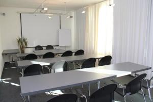 菲尔德施塔特海尔施花园酒店的一间会议室,配有桌椅和白板