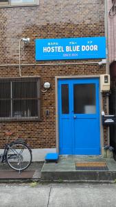 名古屋Hostel Blue Door ホステル ブルードア的建筑物上的蓝色门,旁边是自行车