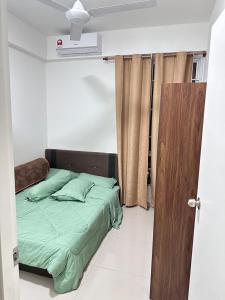 巴西古当Lylinz sierra heights homestay的一间卧室配有一张带绿色床单的床和一扇门