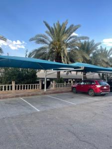 塞卡凯فندق الحنوة的停在一个蓝色天篷停车场的红色汽车