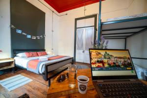 瓦尔帕莱索Maki Hostels & Suites Valparaiso的一间卧室配有一张床和一张桌子上的笔记本电脑