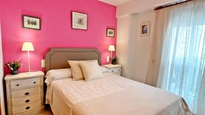 甘迪亚海滩FLORESTA GANDIA - Solo Familias的一间卧室设有粉红色的墙壁和一张带2晚台的床