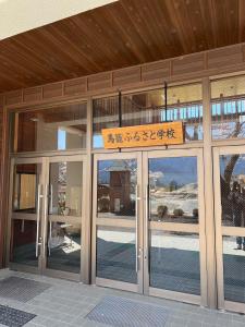 中津川市馬籠ふるさと学校 Magome Furusato Gakkou的建筑物入口,上面有标志