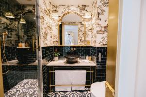 都柏林The Leinster的浴室铺有黑色瓷砖,配有水槽和镜子