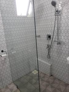 MunyonyoMHP Apartments的带淋浴的浴室和白色瓷砖墙壁