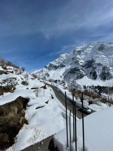 GondlaFort View Home Stay的山前有一条路,有雪覆盖的山