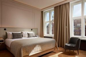赫尔辛基NH Collection Helsinki Grand Hansa的一间卧室配有一张床、一把椅子和窗户。