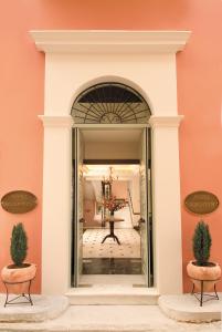 纳夫普利翁波利蒂酒店的拱门通往一个粉红色墙壁的房间