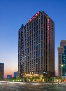 深圳Hongfeng Hotel Nanshan Branch的一座高大的建筑,旁边灯火通明