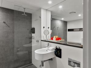 悉尼Hotel Woolstore 1888, Sydney - Handwritten Collection的白色的浴室设有水槽和淋浴。