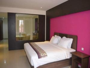 索龙Belagri Hotel And Restaurant的一间卧室配有一张带粉红色墙壁的大床