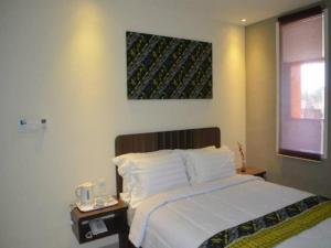 索龙Belagri Hotel And Restaurant的卧室配有一张床,墙上挂着一幅画