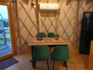 ZabierzówGlamping Pogorzany - Jurty的一间带桌子和绿色椅子的用餐室