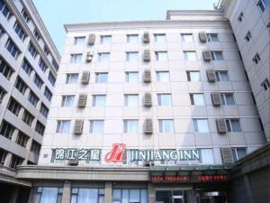 大连Jinjiang Inn - Xishan Road的一座白色的大建筑,上面有标志