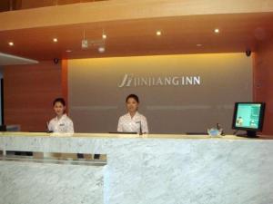 苏州Jinjiang Inn Suzhou Railway Station Wanda Plaza Pinglong Road Metro Station的两名妇女站在房间里柜台