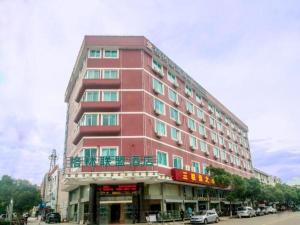 舟山GreenTree Alliance Zhejiang Zhoushan Putuoshan Zhujiajian Scenic Spot Hotel的城市街道上一座高大的红色建筑,有汽车