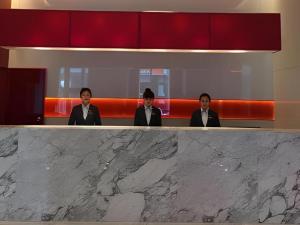 沈阳Jinjiang Metropolo Hotel Shenyang Shengjing Hospital Sanhao Street的坐在柜台上的三人组