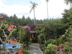 PalasariPuri Eling Blimbingsari Hotel的一座带游泳池、棕榈树和鲜花的度假村